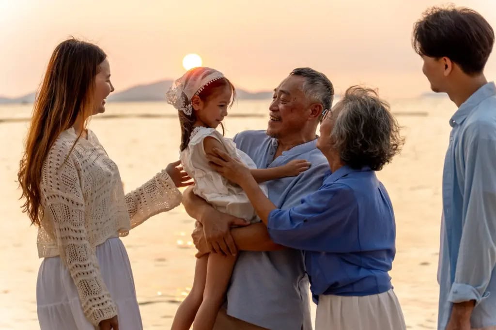 A multi-generational family enjoying a sunset on the beach.