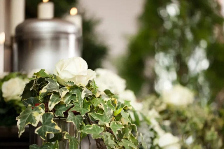 An urn is displayed at a funeral surrounded by candles and flowers