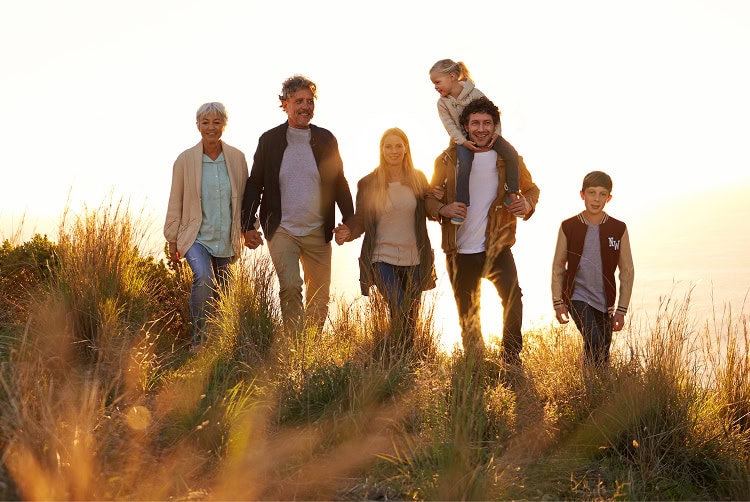 Multi-generational family walking together outdoors on a sunny day.