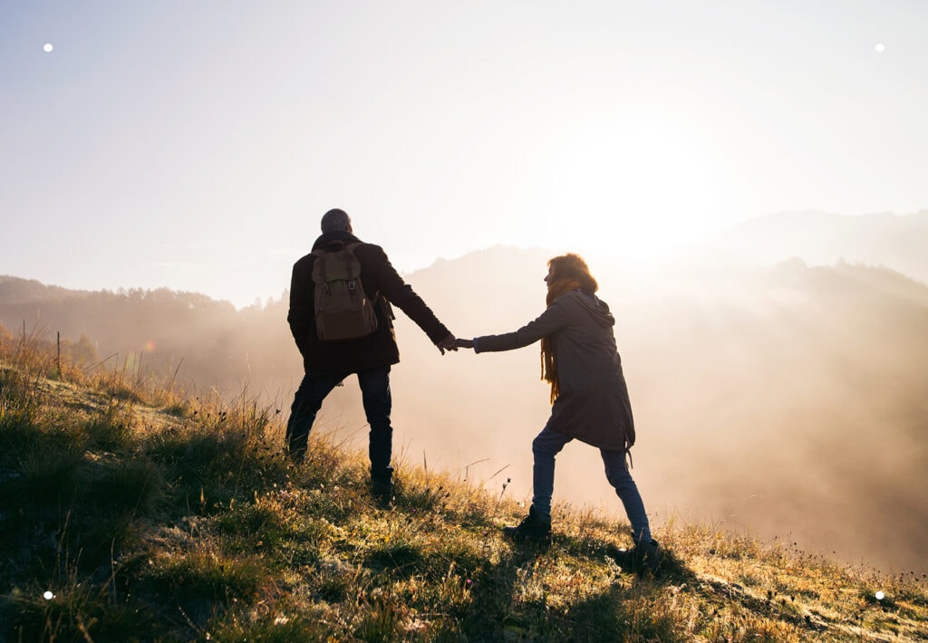 Middle-aged couple walking up a sunlit hill on an autumn morning, symbolizing guidance, support, and peace of mind.
