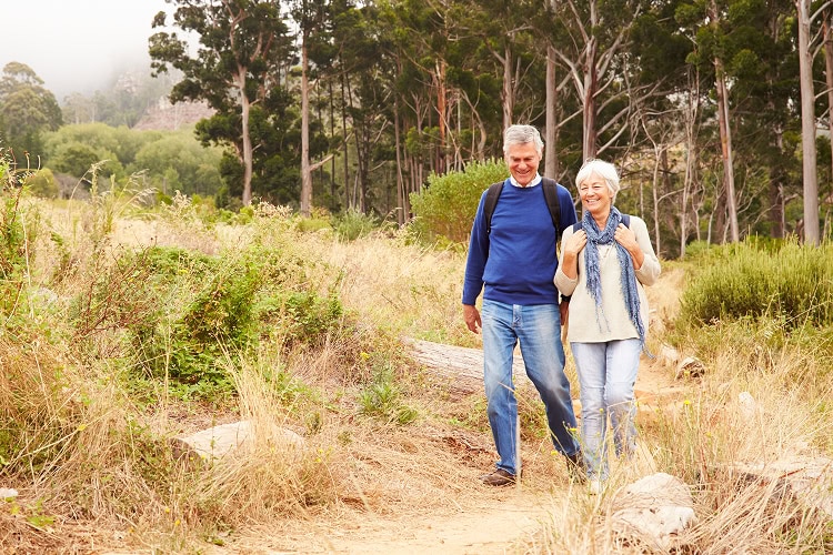 Happy, older couple walking on a forest path.