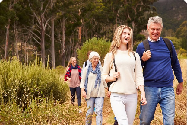 Young woman and older man lead a group of people hiking on a forest trail.