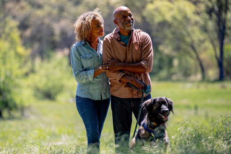 Husband and wife walking with their dog through a memorial forest, symbolizing peace, trust, and comfort in nature.