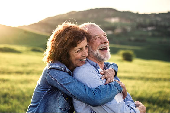 Side view of senior couple embracing outdoors at sunset in spring, symbolizing peace of mind and planning ahead.
