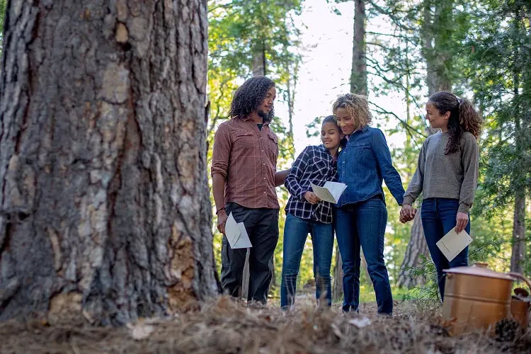 Family gathered for a nature memorial at their memorial tree in a protected forest, honoring a loved one through a peaceful ceremony in nature.