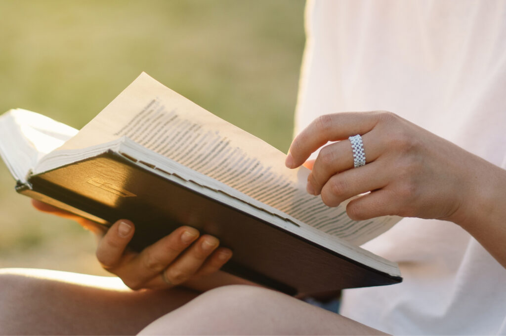 A close-up of a hand turning a page of the Bible.