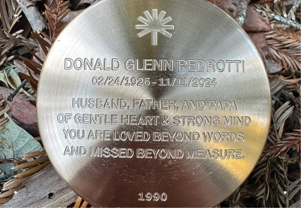 A close-up of memorial marker engraved with a name, dates and personalized sentiment.