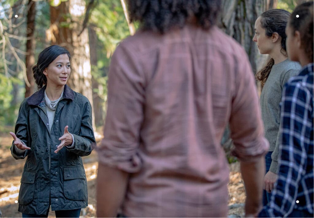 An Everis Guide talking to a small group of people in the forest.